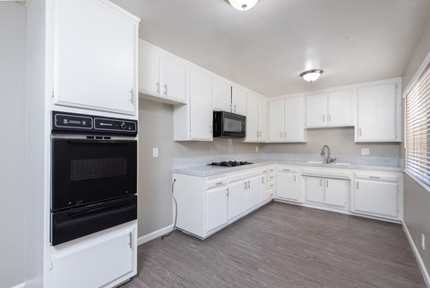 an empty kitchen with white cabinets and black appliances